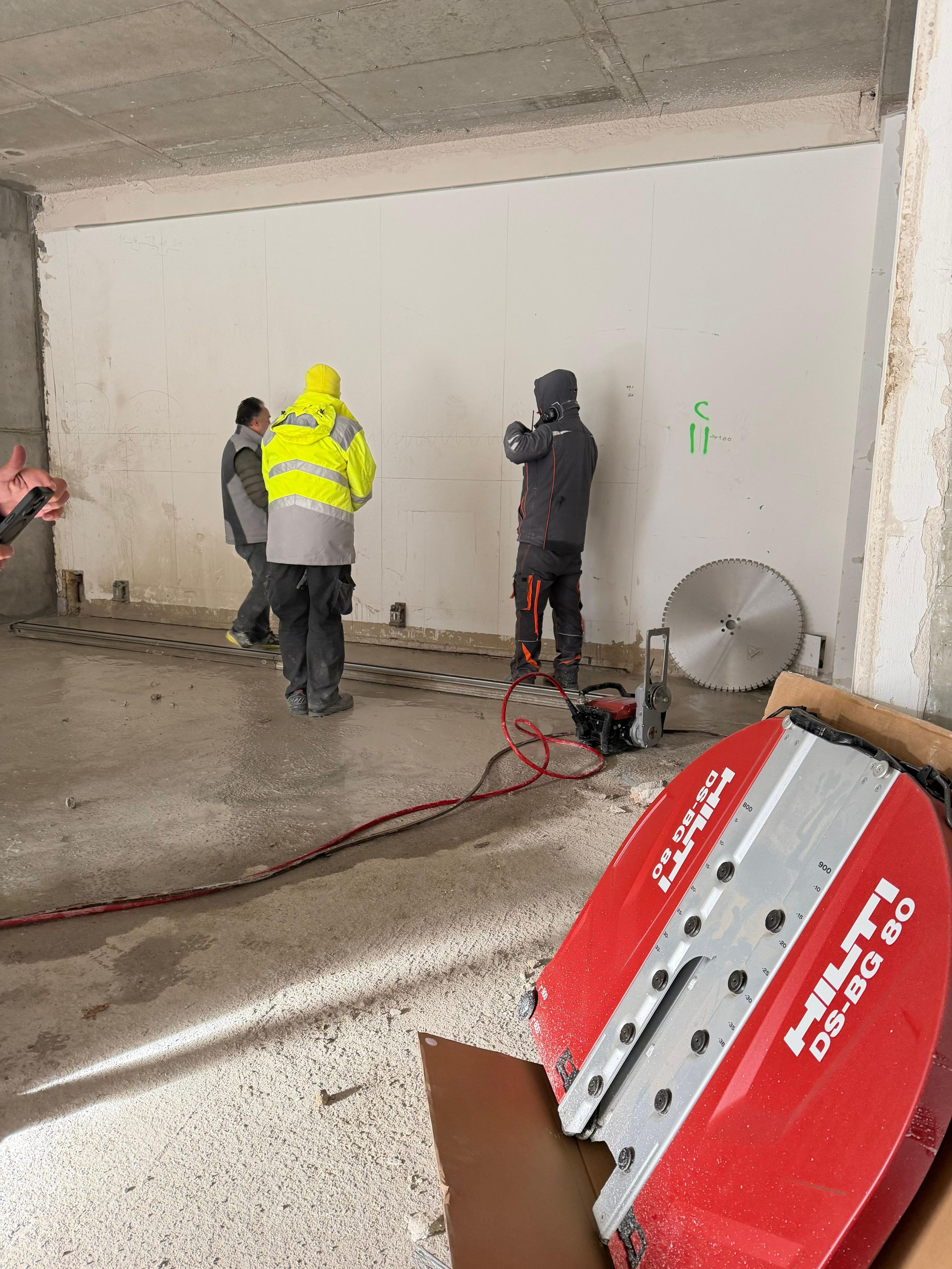 Zwei Mitarbeiter in Warnschutzkleidung bei Bohrarbeiten im Rohbau
