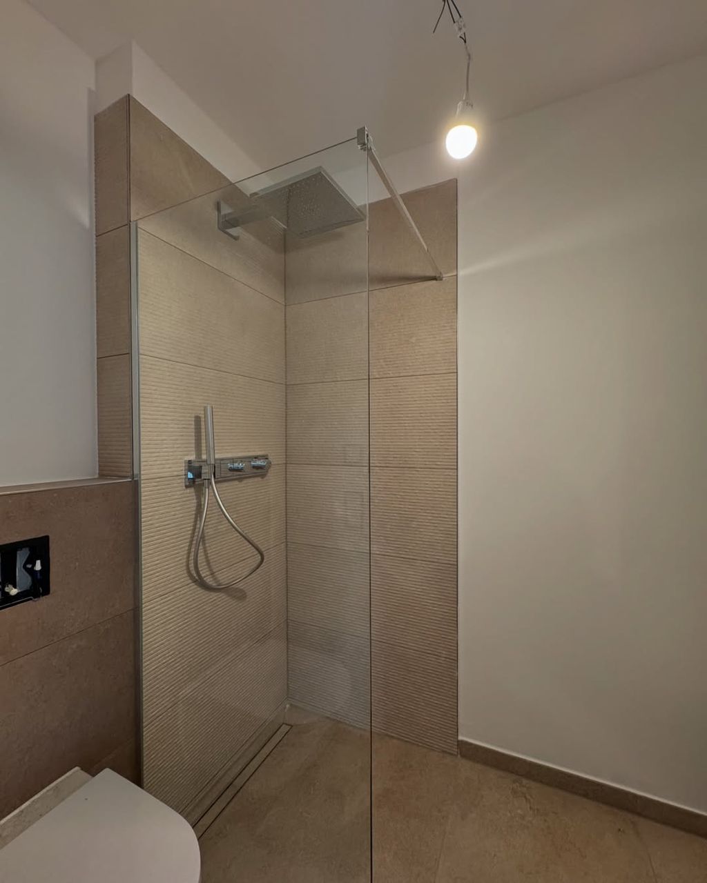 Fertiges Badezimmer mit bodengleicher Dusche und Glasabtrennung